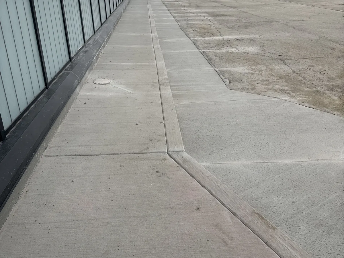 Finished concrete sidewalk and curb along a glass commercial building, commercial concrete flatwork