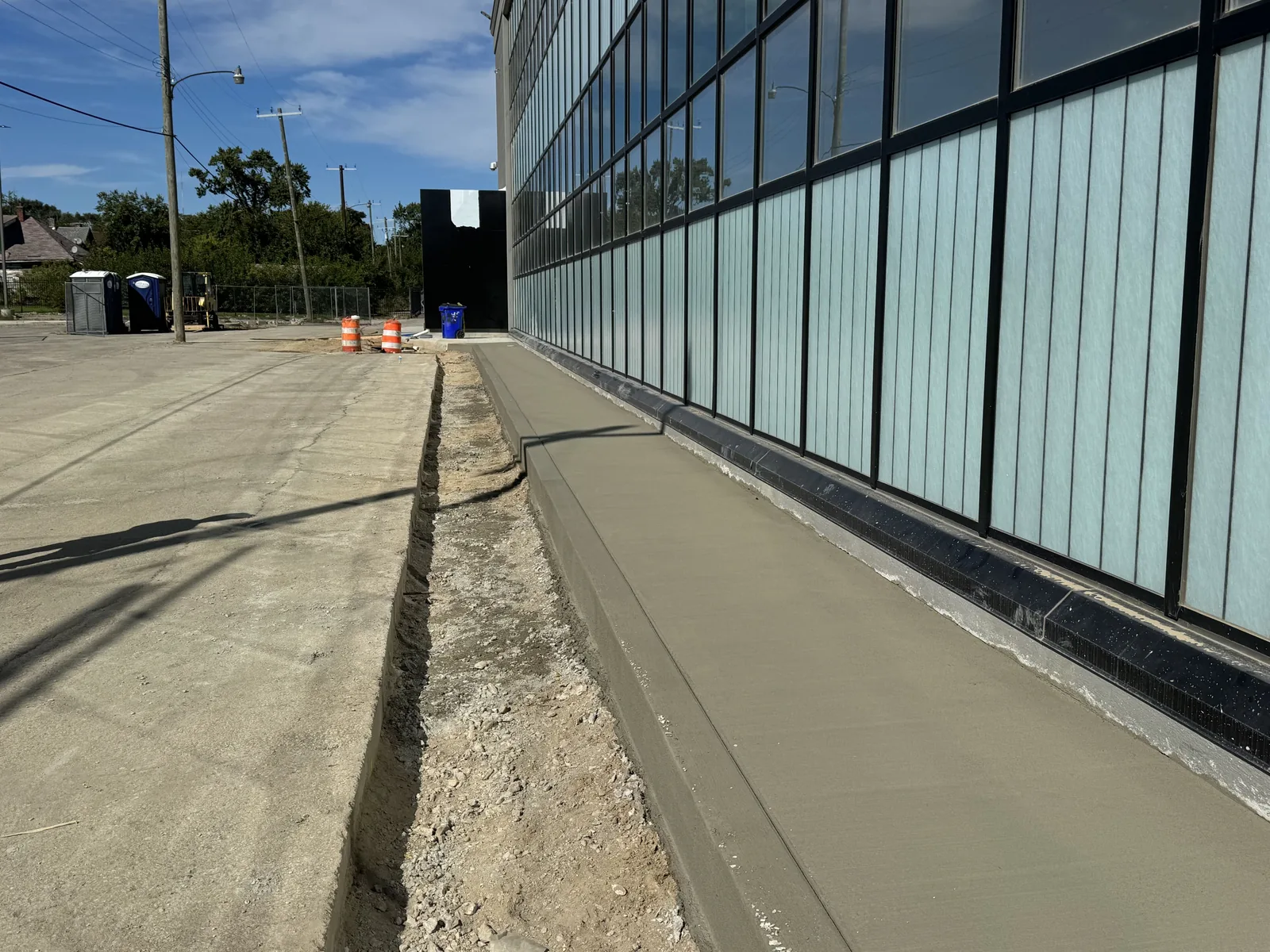 Freshly poured concrete sidewalk along a glass commercial building, commercial concrete flatwork