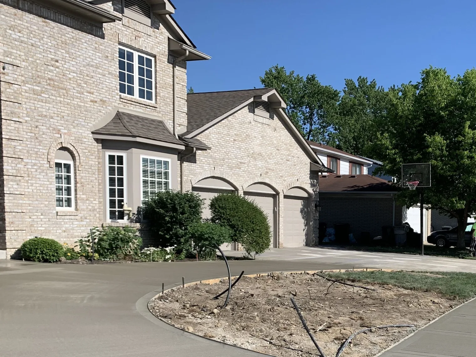New concrete circle driveway and walk curving in front of a brick two story house, concrete driveways
