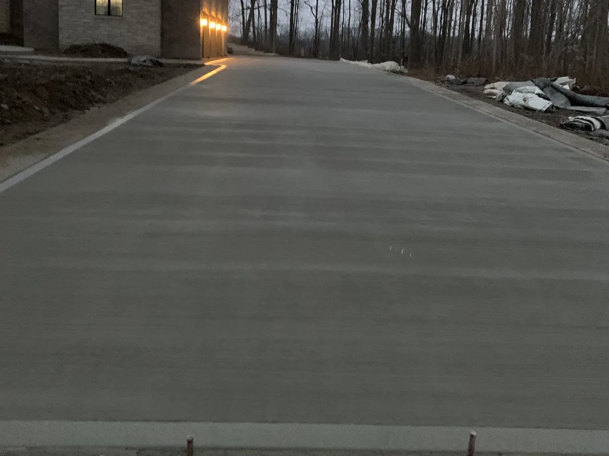 New concrete driveway at dusk running up a wooded lot, concrete driveways