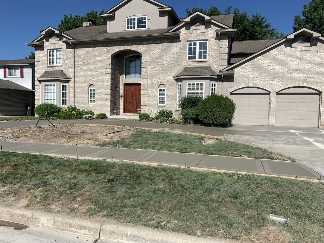 New broom finish concrete walk and driveway apron in front of a brick house, concrete driveways