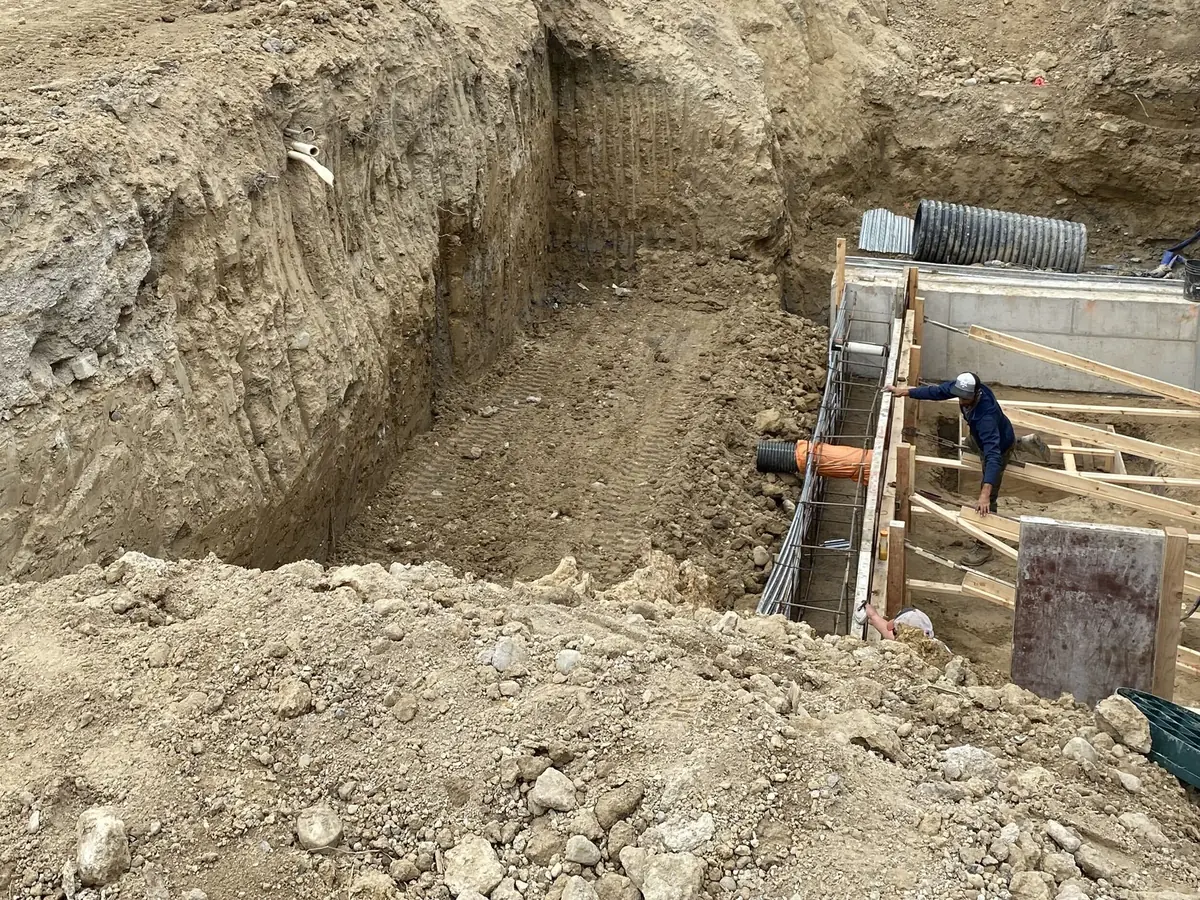 Foundation excavation with forms set for footings and walls beside a house, concrete foundations
