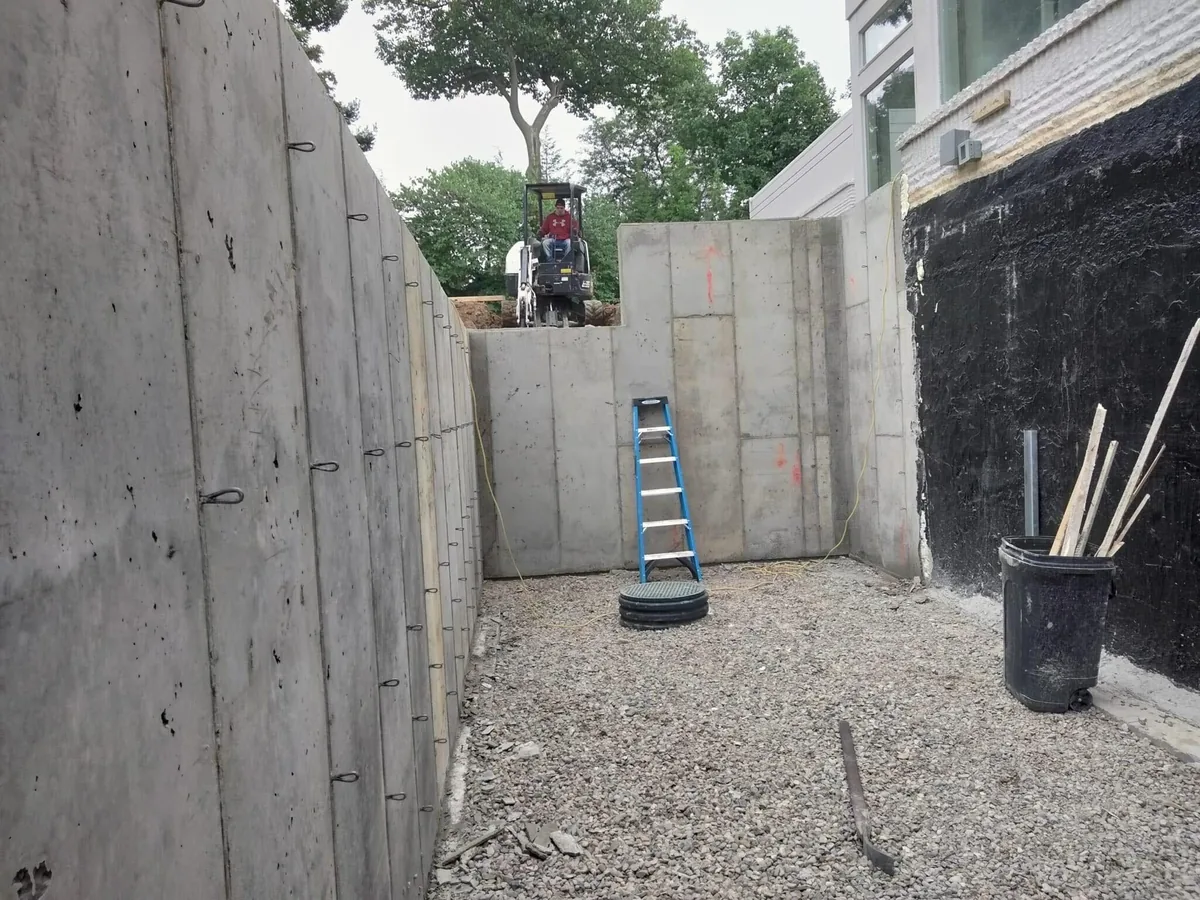 Poured concrete foundation walls beside a waterproofed wall over a gravel base, concrete foundations