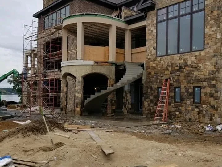 Curved poured concrete staircase rising along a stone house, concrete steps and custom staircases
