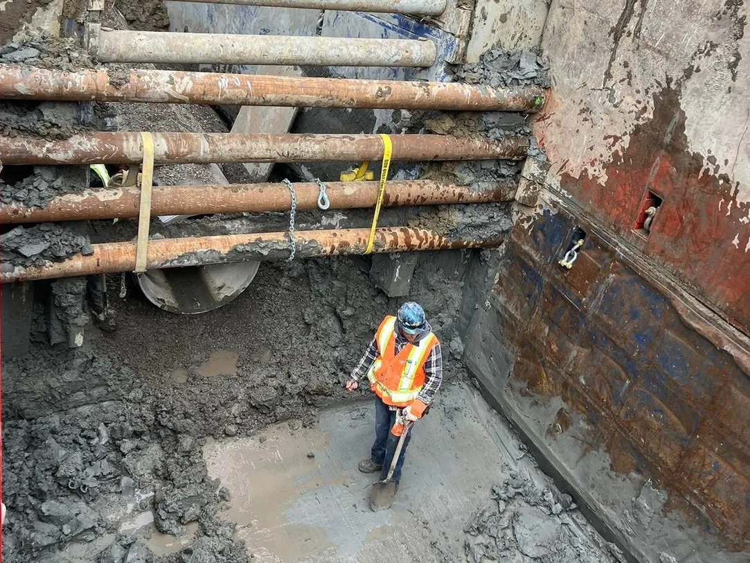 Deep excavation braced with steel trench shoring and a worker at the bottom, excavation and site work