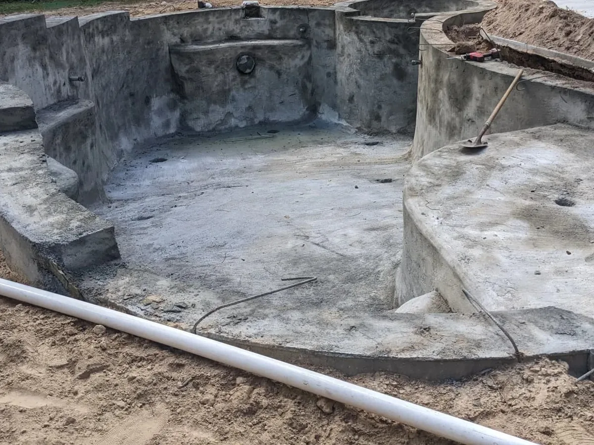 Gunite pool shell with built in steps and a curved bench before tile and plaster, inground pools