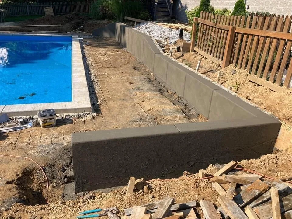 New poured concrete retaining wall beside an inground pool, inground pools