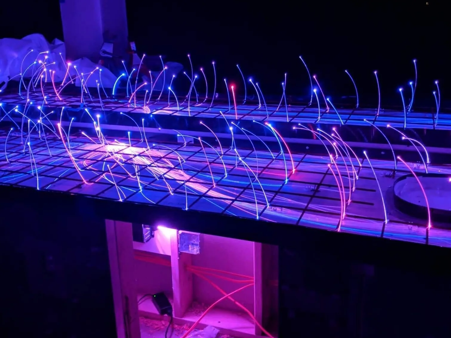 Fiber optic strands glowing over rebar at night before a concrete pour, outdoor living