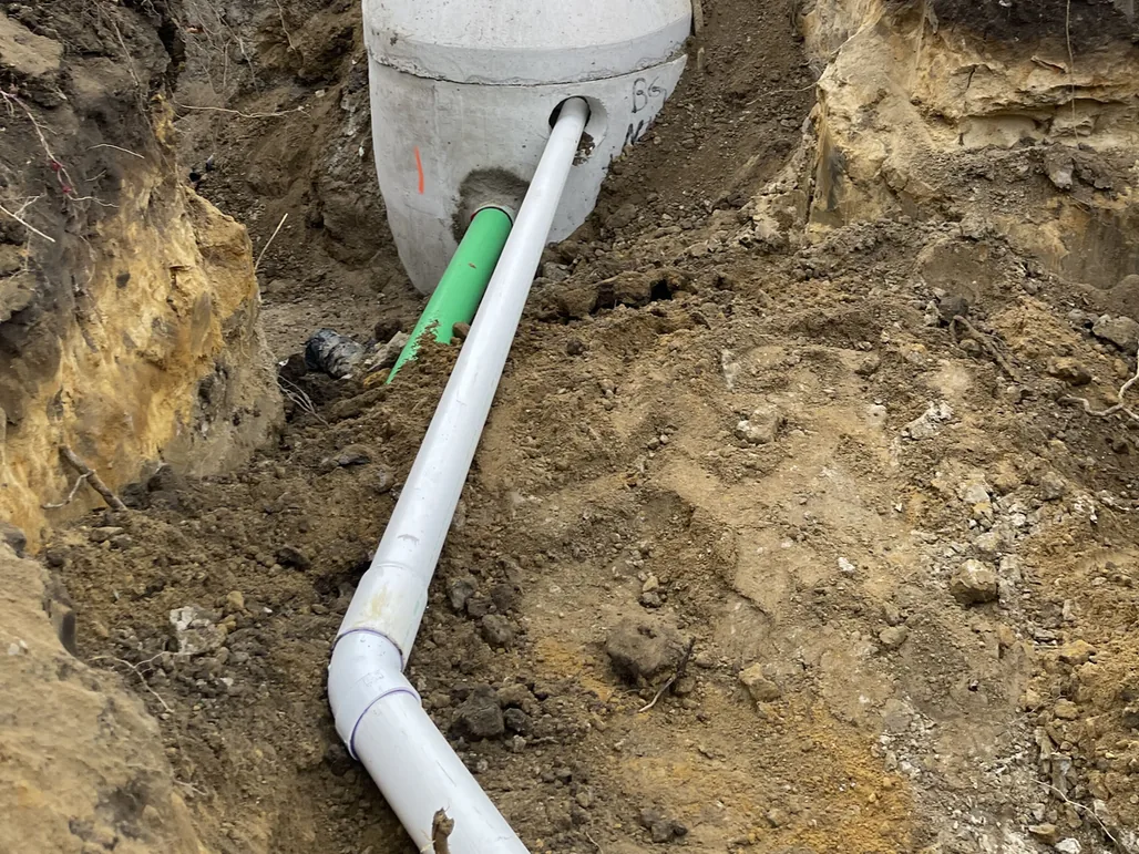 Precast structure with new PVC pipes tied in on a fenced job site, construction project management