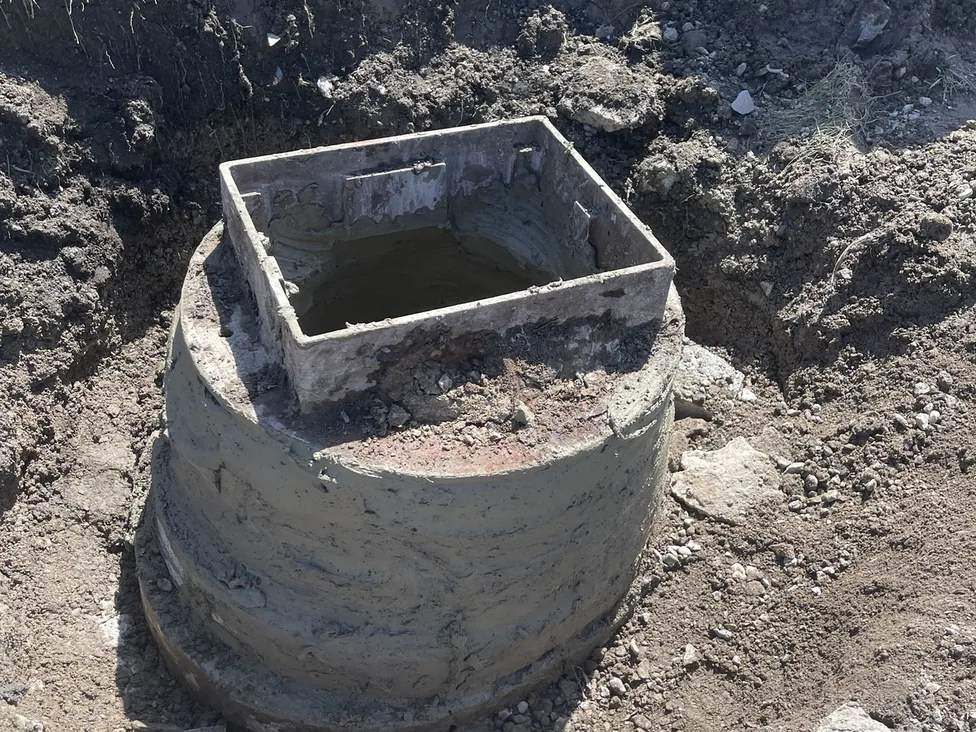 Precast catch basin riser with a square frame mortared on top in an excavation, storm drainage and catch basin installation