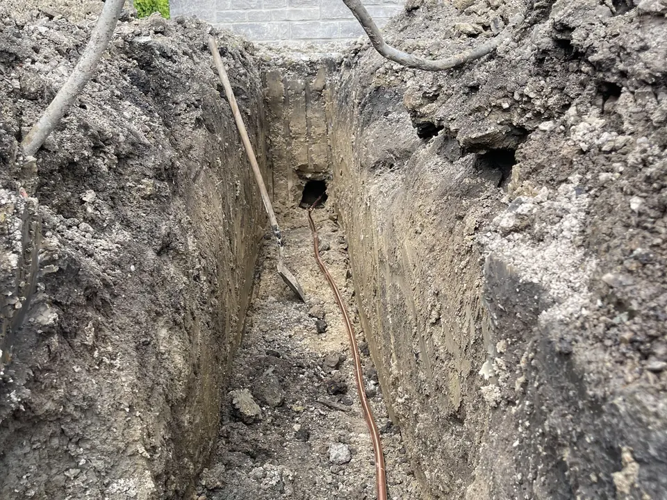 Copper water service line laid along the bottom of a trench running to a house, water main and service line installation
