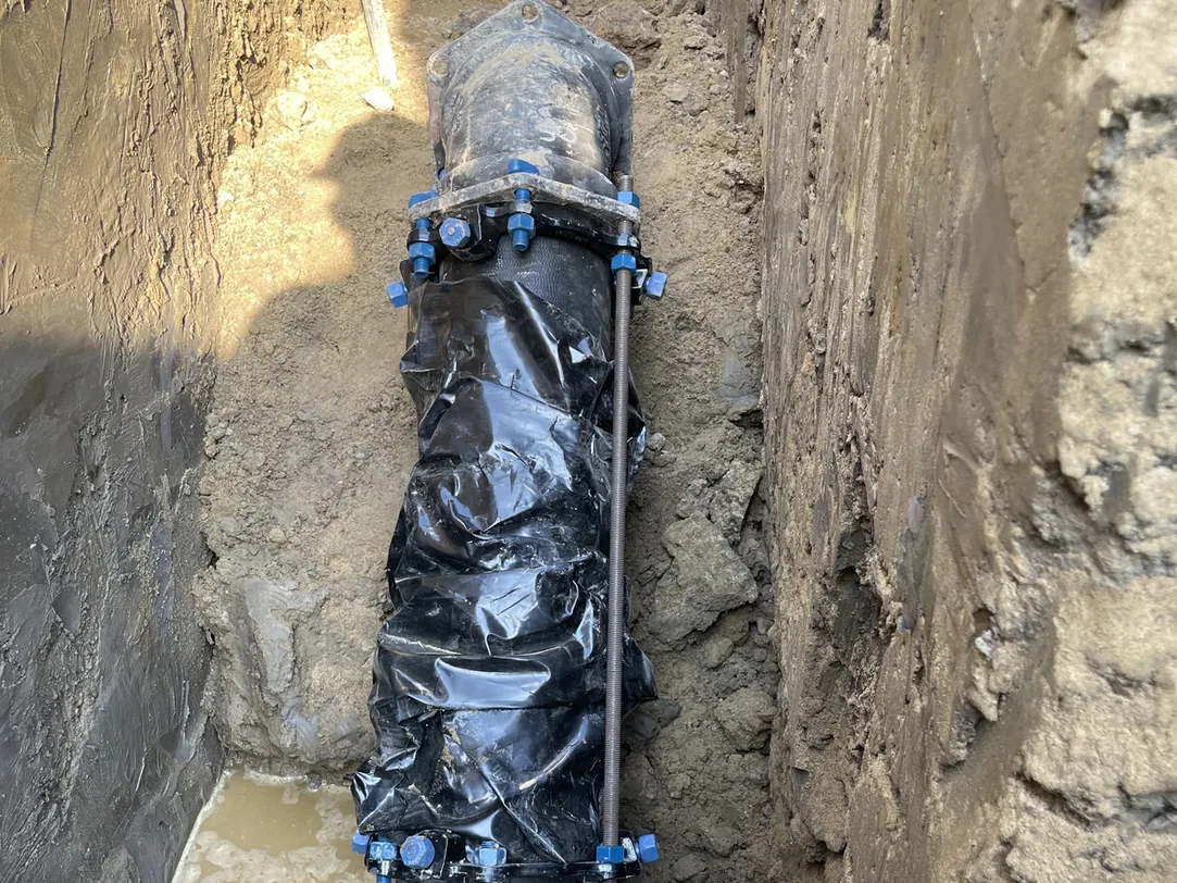 Ductile iron water main wrapped in black poly with restrained joints in a trench, water main installation